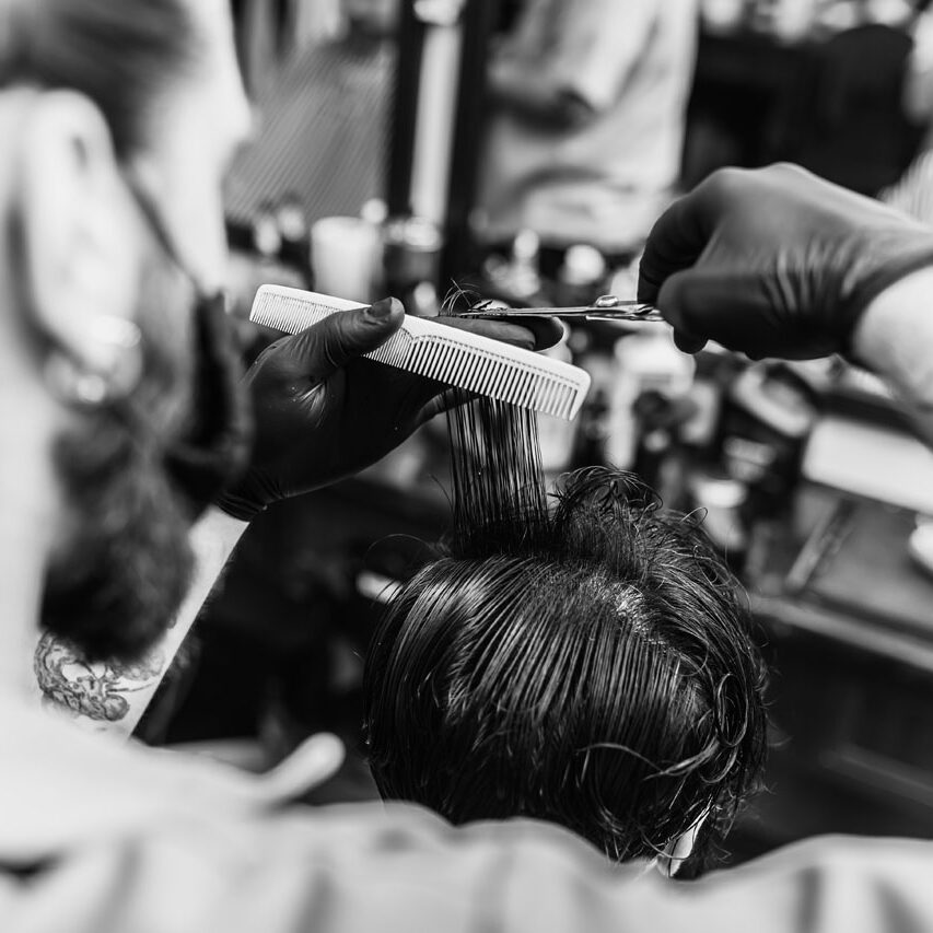 Barber makes a haircut and hair styling in a barbershop, beauty salon. Healthy hair.
